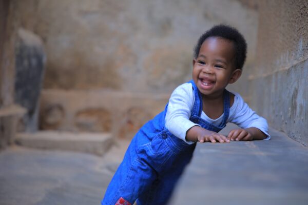 A young child leaning up against a ledge in a stone room