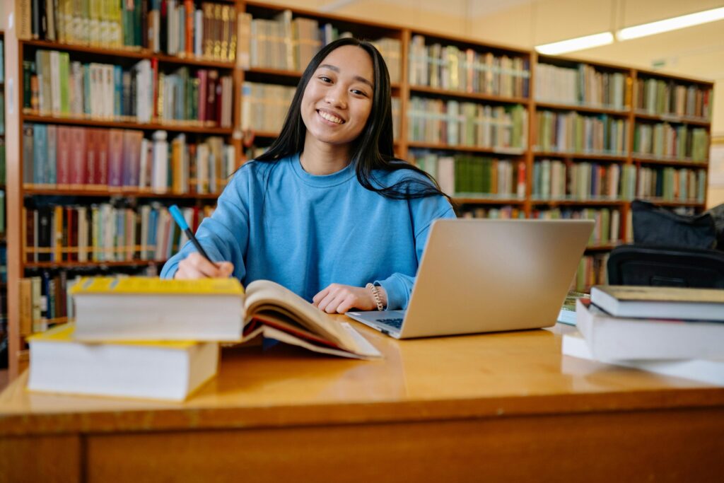 A lady in blue jumper sat at a library desk